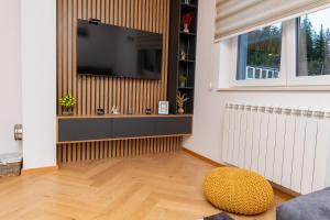 een woonkamer met een flatscreen-tv aan de muur bij Sunčani vrhovi in Jahorina