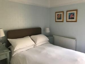 Una cama con sábanas blancas y almohadas en un dormitorio en Lawrenny Lodge, en Barmouth