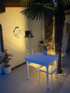 a blue table and two chairs in front of a palm tree at B&B Nathalie in Quartino