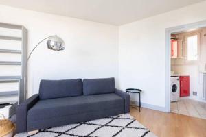 ein Wohnzimmer mit einem blauen Sofa in einem weißen Zimmer in der Unterkunft Appart Plein Soleil Seine Paris 5ème Jardin Plantes in Paris