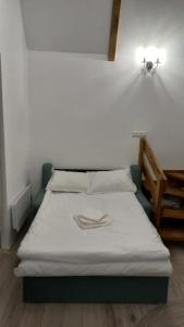ein Bett mit zwei weißen Handtüchern darauf in einem Zimmer in der Unterkunft ALI HOUSE in Poiana Fagului