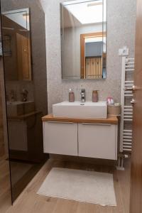 een badkamer met een witte wastafel en een spiegel bij Sunčani vrhovi in Jahorina