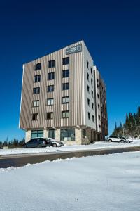 a large building with cars parked in the snow at Sunčani vrhovi in Jahorina