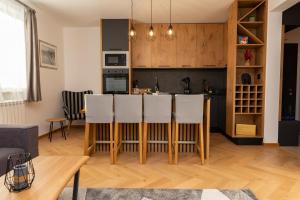 een keuken en een woonkamer met een bar met witte stoelen bij Sunčani vrhovi in Jahorina