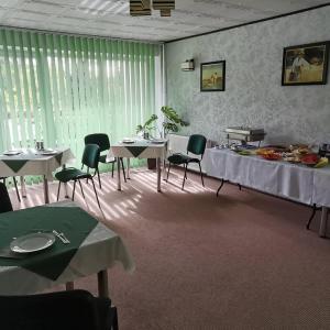 une salle à manger avec des tables, des chaises et des rideaux verts dans l'établissement Usługi Noclegowe i Gastronomiczne dla Ludności Robert Mielcarek, à Kobyla Góra