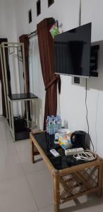 ein Wohnzimmer mit einem TV und einem Couchtisch in der Unterkunft Hotel pondok putri in Batukaras