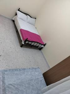 um quarto com uma cama com um cobertor rosa e branco em Hussaini Home em Abu Dhabi