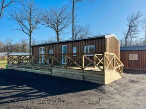 a large wooden cabin with a wooden deck at Equi-lodge vert au coeur des chevaux & de la nature proche Disney avec possibilité de balade poneys in La Houssaye-en-Brie