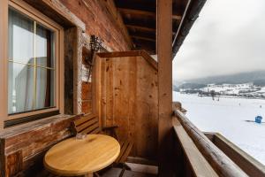einem Holztisch auf der Veranda einer Hütte mit einem Fenster in der Unterkunft Hotel Restaurant Hexenalm in Söll