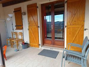 a porch with wooden doors and chairs on a house at Pavillon 5 personnes in Port-la-Nouvelle