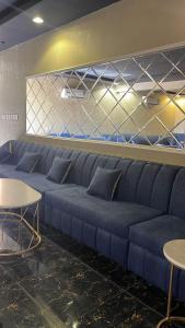 - un grand canapé bleu dans une chambre avec des tables dans l'établissement شاليهات يارا القيروان, à Riyad
