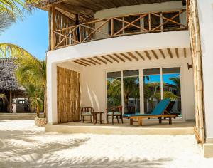 uma villa na praia com cadeiras e mesas em Infinity Beach Boutique Hotel & SPA em Matemwe