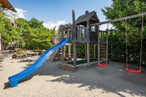 un parque infantil con tobogán azul y columpios en Ferienwohnungen Rebmannhof en Lana