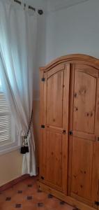 une armoire en bois à côté d'une fenêtre et d'un rideau dans l'établissement Jolie propriété de campagne calme et spacieuse, 