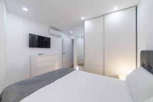 a white bedroom with a bed and a tv at Trendy Homes Lepanto I in Almería