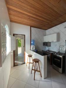 een keuken met een fornuis en 2 krukken. bij Small house in Ilha de Boipeba
