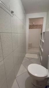 a white bathroom with a toilet and a shower at Casinha Azul in Ilha de Boipeba
