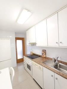 a kitchen with white cabinets and a sink at Olivar Beach by Agencia Poniente in Benidorm