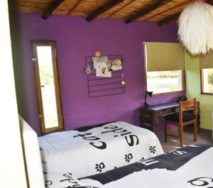 Dormitorio con pared morada, cama y escritorio en La Residencial en Humahuaca