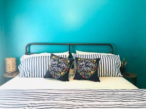 a bed with three pillows and a blue wall at Peekskill Guesthouse - Downtown Peekskill in Peekskill