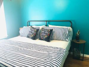 a bed with three pillows and a blue wall at Peekskill Guesthouse - Downtown Peekskill in Peekskill
