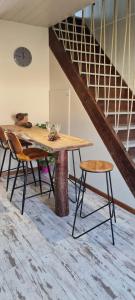 una mesa y sillas en una habitación con escalera en Gite du bourbouillon, en Largillay-Marsonnay