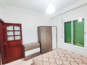 a bedroom with a bed and a wooden door at SkyRise Khemisset 2 : 2 bedrooms in Khemisset