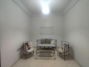 a white room with three chairs and a couch at SkyRise Khemisset 2 : 2 bedrooms in Khemisset