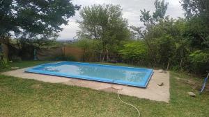 una piscina azul en un patio con árboles en Wayra Waka en Villa Giardino