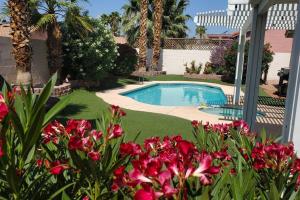 a swimming pool in a yard with pink flowers at Comfortable Family Home in Las Vegas