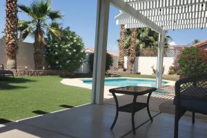 eine Terrasse mit einem Tisch, Stühlen und einem Pool in der Unterkunft Comfortable Family Home in Las Vegas