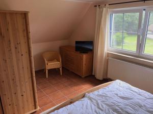 a bedroom with a bed and a dresser and a window at Dycke Haus 6 in Zudar