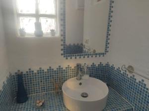 uma casa de banho em azulejos azuis com um lavatório e um espelho em Cuevas del Sol em Gorafe