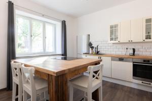 Urige Wohnung mit zwei Betten und genialer Küche في Mügeln: مطبخ مع طاولة خشبية ودواليب بيضاء