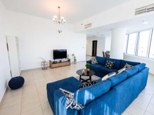 a living room with a blue couch and a tv at Avantha By Afi luxury 2BHK apartment in Dubai