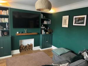 a living room with a green wall with a fireplace at Millwright Villa - sleeps 7 in Lincolnshire