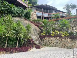 un edificio con palmeras y una pared de piedra en Casa com Piscina, Rede Suspensa e Praia Privativa, en Mangaratiba 68 fotos más
