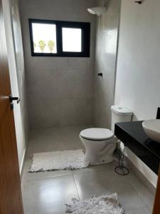 a bathroom with a toilet and a sink and a window at Casa de campo 1h30 de SP Ninho verde 1 in Porangaba