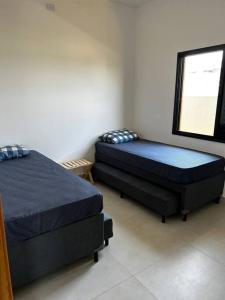 two twin beds in a room with a window at Casa de campo 1h30 de SP Ninho verde 1 in Porangaba
