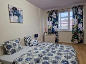 Schlafzimmer mit einem Bett und einem Fenster mit Vorhängen in der Unterkunft Уютен 2-стаен Апартамент в Центъра на Добрич in Dobritsch