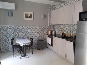una cocina con armarios blancos y una mesa con sillas. en Casa azul & blanca, en Banyuls-sur-Mer