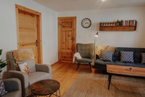 a living room with a couch and chairs and a clock at Ferienwohnung Wanderslust zentral in Ilmenau in Ilmenau