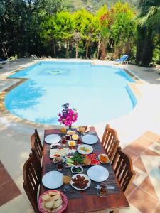 a table with food on it next to a swimming pool at Kızılbük Ahşap Evleri in Datca