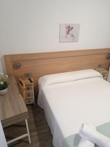 a bedroom with a white bed and a wooden table at ApartamentosTuristicos Avila Puerta del Alcazar 0-1 in Ávila +7 photos
