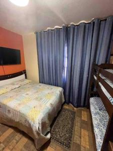 Un dormitorio con una cama y una cortina azul. en Casa em frente a Praia das Dunas, Cabo Frio - RJ, en Cabo Frío 17 fotos más