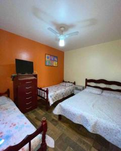 een slaapkamer met 2 bedden en een plafondventilator bij Casa em frente a Praia das Dunas, Cabo Frio - RJ in Cabo Frio