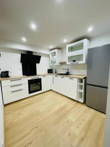 a kitchen with white cabinets and a wooden floor at Charmant T3 des Pyrénées in Argelès-Gazost