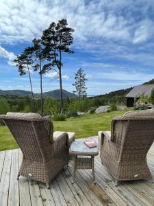 two wicker chairs sitting on a wooden deck at Cabin near Pulpit Rock in Strand