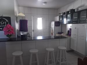 a kitchen with a counter with stools and a refrigerator at Chácara Família Nacer in Serra de São Bento