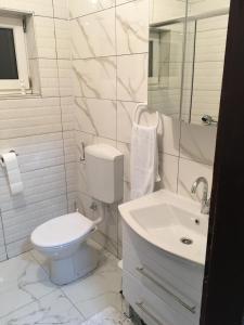 La salle de bains blanche est pourvue de toilettes et d'un lavabo. dans l'établissement Apartman Marija, à Kupres